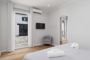 a white bedroom with a bed and a tv on the wall at Casa da eira in Ribeira Grande