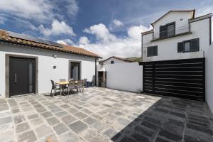 a patio with a table and chairs and a building at Casa da eira in Ribeira Grande