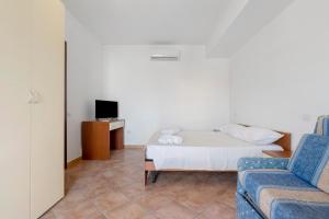 a room with a bed and a couch and a tv at Daluef Alloggi in Assemini