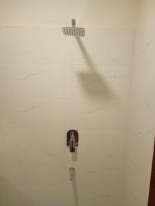a white tiled wall with a valve in a bathroom at Hotel Vijay Palace in Agra +46 photos