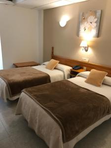 Habitación de hotel con 3 camas y mantas marrones en Hostal Alcázar, en Toledo