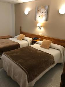 um quarto de hotel com duas camas e duas lâmpadas em Hostal Alcázar em Toledo