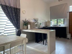 a kitchen with a counter and a table with chairs at RUANG by ZD in Pekan
