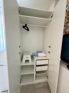 a small closet with white shelves and a sink at Le Marronnier - Studio confortable proche de Lyon in Charbonnières-les-Bains +1 photo