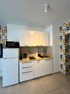 a kitchen with white cabinets and a white refrigerator at Le Marronnier - Studio confortable proche de Lyon in Charbonnières-les-Bains