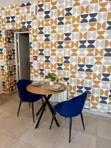 a table and chairs in a room with a wall at Le Marronnier - Studio confortable proche de Lyon in Charbonnières-les-Bains