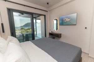 a bedroom with a bed and a large window at Kefalos View in Vrachonisída Palaiókastro