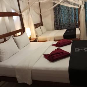 two beds in a hotel room with towels on them at Sigiri Holiday Bungalow in Sigiriya