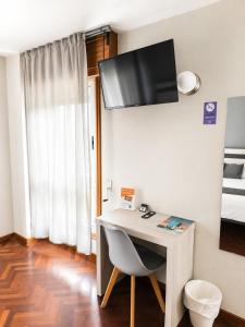 a room with a desk with a television on the wall at Alda Puerta Coruña in A Coruña