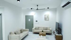 a living room with two couches and a tv at Rima Salalah in Salalah