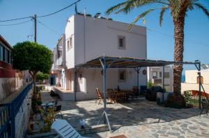 a white building with a table and chairs and a palm tree at GLIPTIS Apartments in Chios