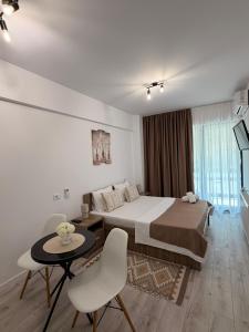 a bedroom with a bed and a table and chairs at Apartament Căciulata Duo cu 2 camere independente in Căciulata