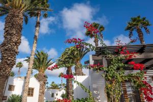 a building with palm trees and flowers at Ona Las Brisas in Playa Blanca