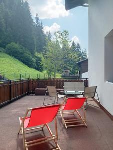 a patio with two red chairs and a table at Hotel Genzianella in Presenaio