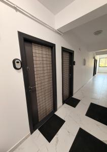 a room with two doors and black mats on the floor at Apartament Căciulata Duo cu 2 camere independente in Căciulata