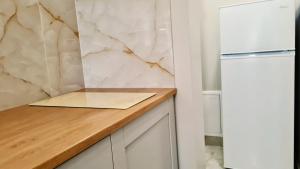 a kitchen with a cutting board on a counter next to a refrigerator at Teodor Apartment in Budraičiai