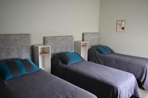 drei Betten in einem Zimmer mit blauen Kissen in der Unterkunft Coty C in Saladillo + 3 Fotos