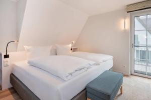 a white bed with a blue stool in a bedroom at Fischerdorf DDH Hafftraum in Zirchow