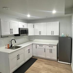 a kitchen with white cabinets and a black refrigerator at AYBAM's House in Winnipeg