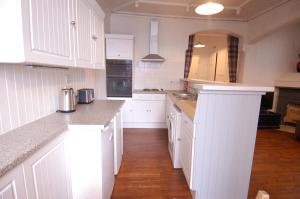 a white kitchen with white cabinets and a wooden floor at Baker Street Retreat in Stirling