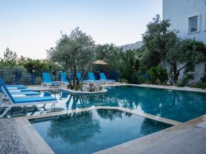 a swimming pool with blue chairs and a table and chairs at Karma homes in Turunç