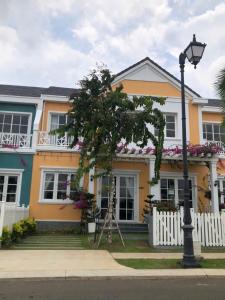 a yellow house with a light pole in front of it at Villa SeriGold - NovaWorld Phan Thiết in Tiến Thành