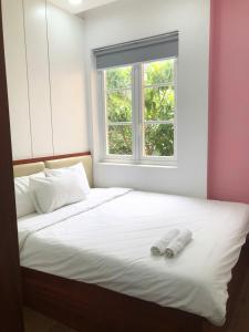 a bed with two white pillows and a window at Villa SeriGold - NovaWorld Phan Thiết in Tiến Thành