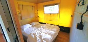 a small room with a white bed and a window at Tent Ween at Glamping Verbaarum in Bedum