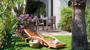 a garden with a bench and a table with flowers at Mangio Fango Hotel et Spa in Saintes-Maries-de-la-Mer