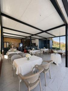 a restaurant with white tables and chairs and windows at LakeFront House in Shirokë
