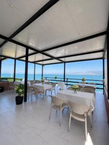 a restaurant with white tables and chairs and the ocean at LakeFront House in Shirokë