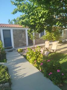 a walkway in front of a house with two chairs and flowers at Lilly of Lemnos in Roussopoúlion