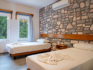 a bedroom with two beds and a stone wall at Karma homes in Turunç
