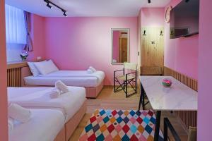 a pink room with two beds and a table at FourMountains-Igman in Sarajevo