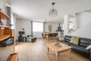 a living room with a black leather couch and a table at Haus Redi in Sasbach in der Ortenau