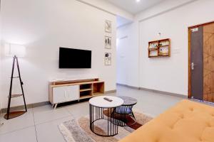 a white living room with a tv and a table at FabHotel Casa Mandrem in Mandrem