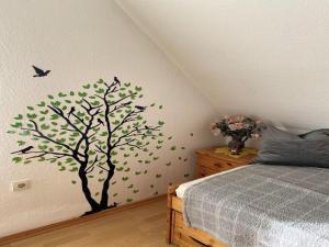 a tree with leaves and a bird on a bedroom wall at Ferienwohnung Sonnenschein mit Balkon in Lage