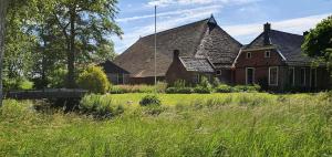 a large house with a grass field in front of it at Tent Ween at Glamping Verbaarum in Bedum