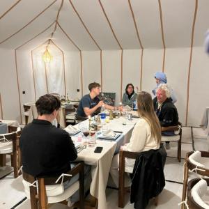 a group of people sitting around a table in a tent at Best-Merzouga traditional camps in Merzouga +49 photos
