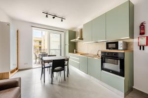 a kitchen with green cabinets and a table and chairs at GZR F51 Bedroom in Penthouse in Il-Gżira +5 photos