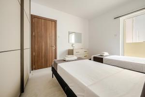 a white bedroom with two beds and a window at GZR F51 Bedroom in Penthouse in Il-Gżira