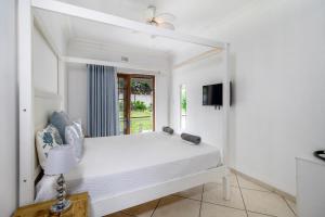 a white bedroom with a bed and a mirror at Comfort on Cabot in Edenvale