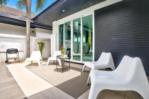 a patio with white chairs and a table at Pool Villa Pattaya Jomtien Beach - Palm Oasis C4 in Jomtien Beach