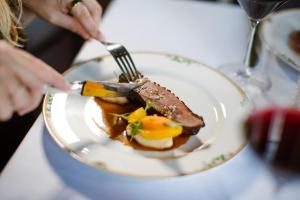 a person eating food on a plate with a fork and knife at Stadspaleis Hotel & Restaurant OldRuitenborgh in Vollenhove