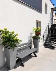 a bench next to a building with two potted plants at Apartamenty Adabet in Kępno