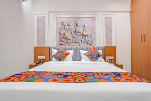 a bedroom with a large white bed with colorful pillows at FabHotel Royal Midway in Gandhinagar