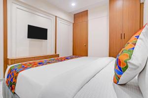a bedroom with a white bed with a colorful pillow at FabHotel Royal Midway in Gandhinagar