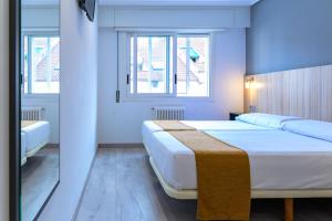 a bedroom with two beds and two windows at Alda Altiana in Ourense