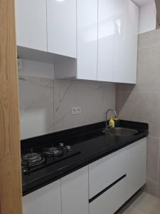 a white kitchen with a sink and white cabinets at Suite Ania in Imejoudene