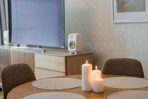 two white candles sitting on a wooden table with chairs at Nordic Nova II by Elys Collection in Rovaniemi